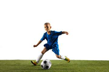 Young boy as a soccer or football player in sportwear making a feint or a kick with the ball for a goal on white studio background. Fit playing boy in action, movement, motion at game.