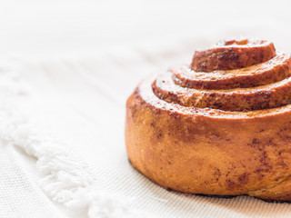 Confectionery baking. Sweet fresh soft roll bun with cinnamon on white background. Cinnabon closeup