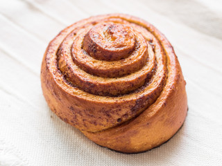 Confectionery baking. Sweet fresh soft roll bun with cinnamon on white background. Cinnabon closeup