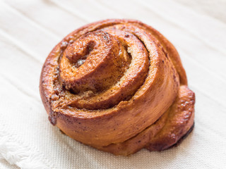 Confectionery baking. Sweet fresh soft roll bun with cinnamon on white background. Cinnabon closeup