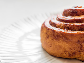 Confectionery baking. Sweet fresh soft roll bun with cinnamon on white background. Cinnabon closeup