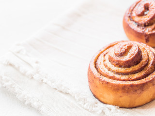 Confectionery baking. Sweet fresh soft roll bun with cinnamon on white background. Cinnabon closeup