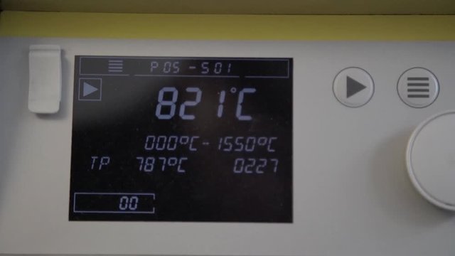 Rising temperature on extremely high temperature oven in dental clinic. Ceramic teeth baking in special furnace machine. Making of artificial teeth by dental technician