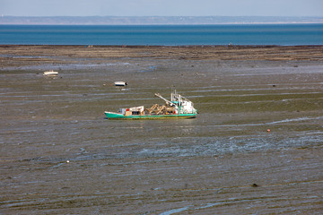 Boats on dry land at the beach at low tide in Cancale famous oysters production town, Brittany,...