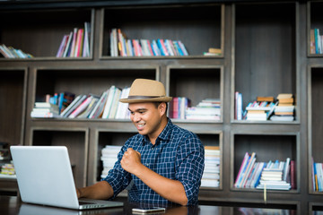 Young casual businessman using laptop, smartphone for working.