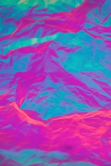Abstract background of neon colours from crumpled gift paper and backlight