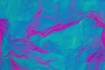 Abstract background of neon colours from crumpled gift paper and backlight