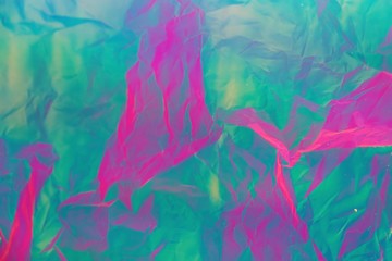 Abstract background of neon colours from crumpled gift paper and backlight