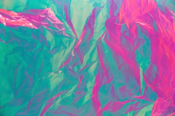 Abstract background of neon colours from crumpled gift paper and backlight