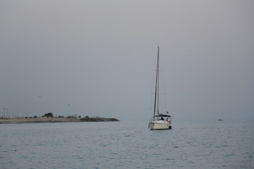 The yacht is in the sea near the shore lowering the sails