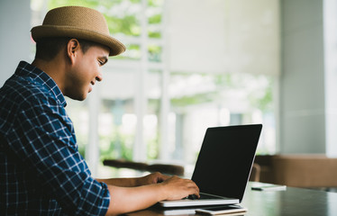 Young casual businessman using laptop, smartphone for working.