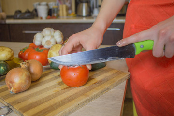 woman cooking healthy meal in the kitchen. Cooking healthy food at home. Woman in kitchen preparing vegetables. Chef cuts the vegetables into a meal