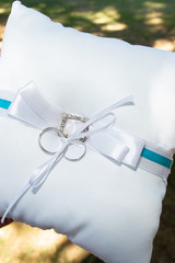 wedding rings on a cushion with blue ribbon