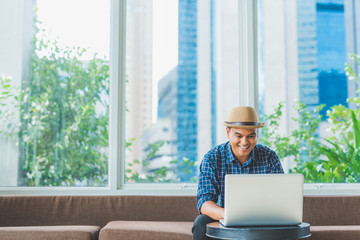 Young casual businessman using laptop, smartphone for working.