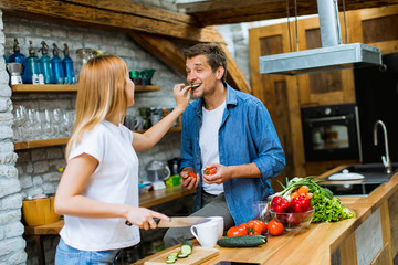 Lovely cheerful couple cooking dinner together and having fun at rustic kitchen