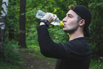 male athlete drinking water from a bottle after a run.