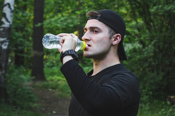 male athlete drinking water from a bottle after a run.