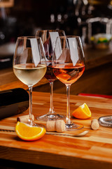 Glasses of white, rose and red wine are on the table, a bottle and corks are nearby. Glasses are on the table in the bar in the restaurant. Background image. copy space