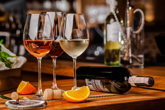 Glasses of white, rose and red wine are on the table, a bottle and corks are nearby. Glasses are on the table in the bar in the restaurant. Background image. copy space