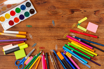 colorful pencils, markers and pens composition mock-up Back to school concept with stationery office supplies on a brown wooden background with copy space top view