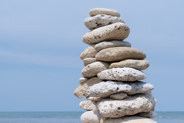 Fototapeta na wymiar Pile of pebbles on a beach with blue sky water background