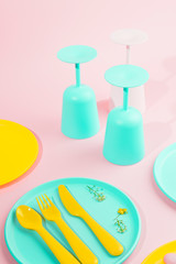 Bright colored plastic picnic utensils. Pink, yellow, blue colors in the bowl. Photo in hard light. Copy space