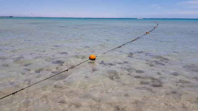 rope with buoys in the sea. Closeup photo. Plastic floating buoys connected in line by rope lying on the sea beach.