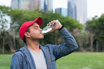 Young handsome asian man drinking water