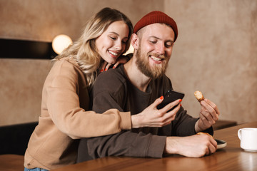 Happy young loving couple in cafe drinking coffee have a breakfast using mobile phone.