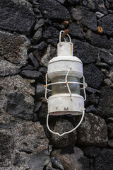 Antique white metal lamp, hanging on a stone wall