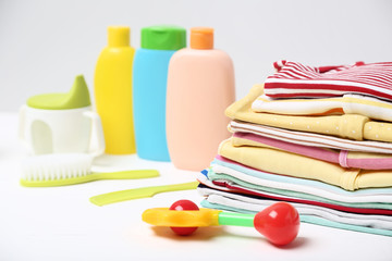 Colorful clothes with toys and baby supplies on white background