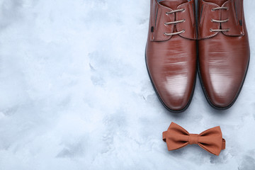 Male leather shoes with bow tie on grey background