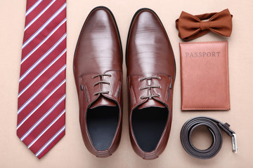 Male leather shoes with passport and accessories on beige background