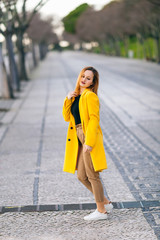 Obraz premium portrait of a girl in a yellow coat walking in street. Female fa