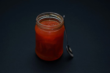 Glass jar of jam on a dark background
