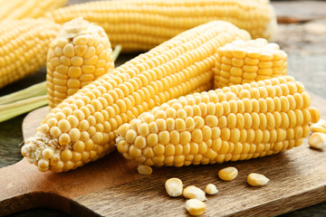 Ripe corn on brown cutting board