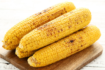 Grilled corn with cutting board on wooden table