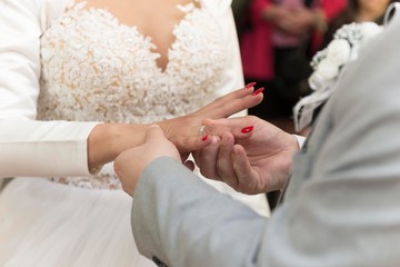 groom putting bride ring on hand