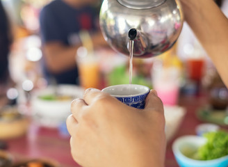 tea pouring hand close up at restuarant with blurry people background