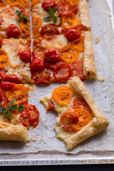 Roasted tomato tart puff pastry on parchment paper, close up