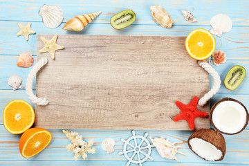 Wooden blank frame with seashells and fruits on blue table