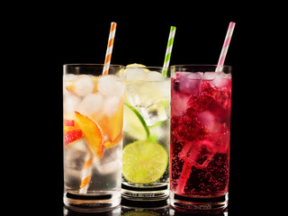 Delicious summer  lemonades with ice,berry, peach and lime on black background. Three glass with cold, fresh drink or coctail on black table