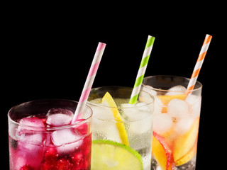 Delicious summer  lemonades with ice,berry, peach and lime on black background. Three glass with cold, fresh drink or coctail on black table