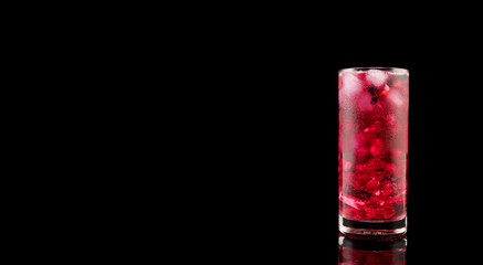 Sweet pomegranate with ice and berry on black background. Delicious summer red lemonade/cold tea.