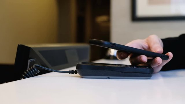 The hand of a young unidentified woman pays for accommodation at the hotel using a smartphone and NFS paypass payment system. The concept of face-free settlement