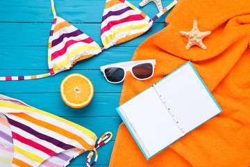 Obraz premium Fashion swimsuit with starfish and notepad on blue wooden table