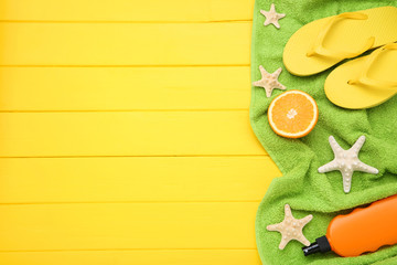 Fashion clothing with starfishes, sunscreen and orange fruit on yellow wooden table