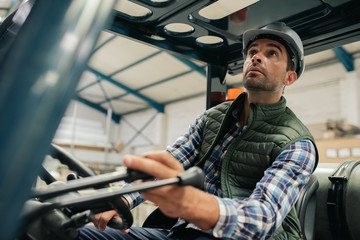Forklift driver carefully moving stock around a warehouse floor