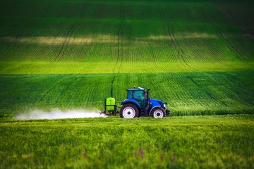 Photo sur Plexiglas Tracteur Farming tractor plowing and spraying on field