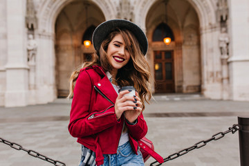 Beautiful caucasian woman smiling to camera while drinking latte beside museum. Adorable chilling...